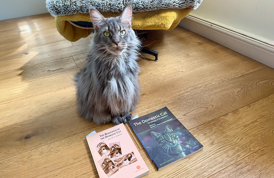 Shae sitting beside two well-used books about cat behaviour