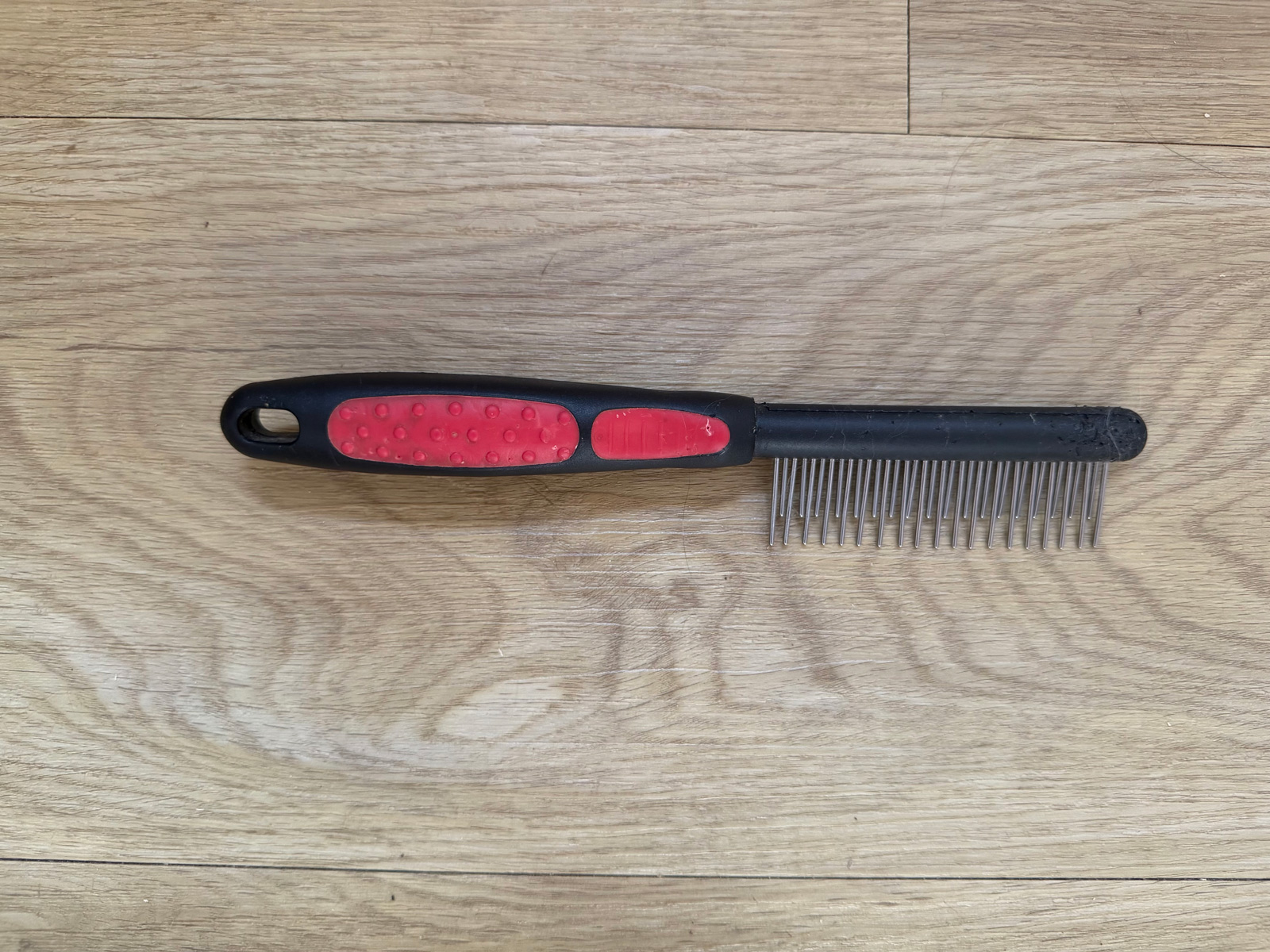 Shae’s black and red rotating-pin comb laid flat to show its alternating tooth lengths